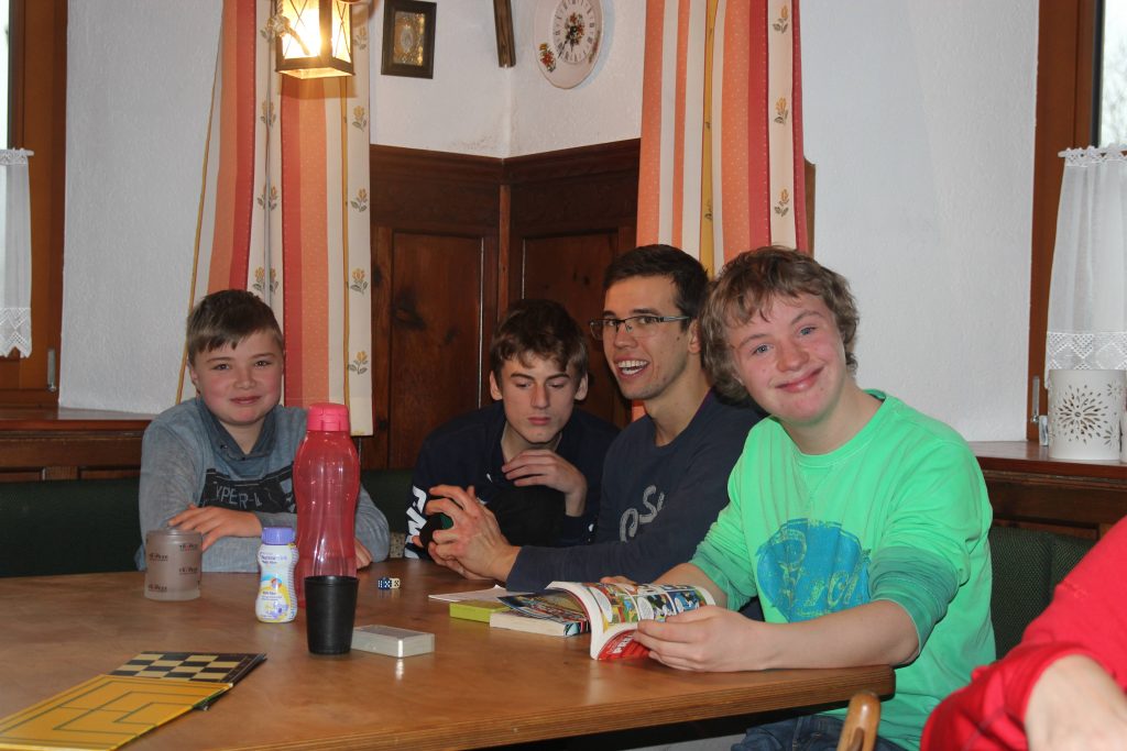 vier Jungs sitzen am Tisch und spielen