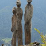 Foto von drei großen Holzfiguren auf einem Fels